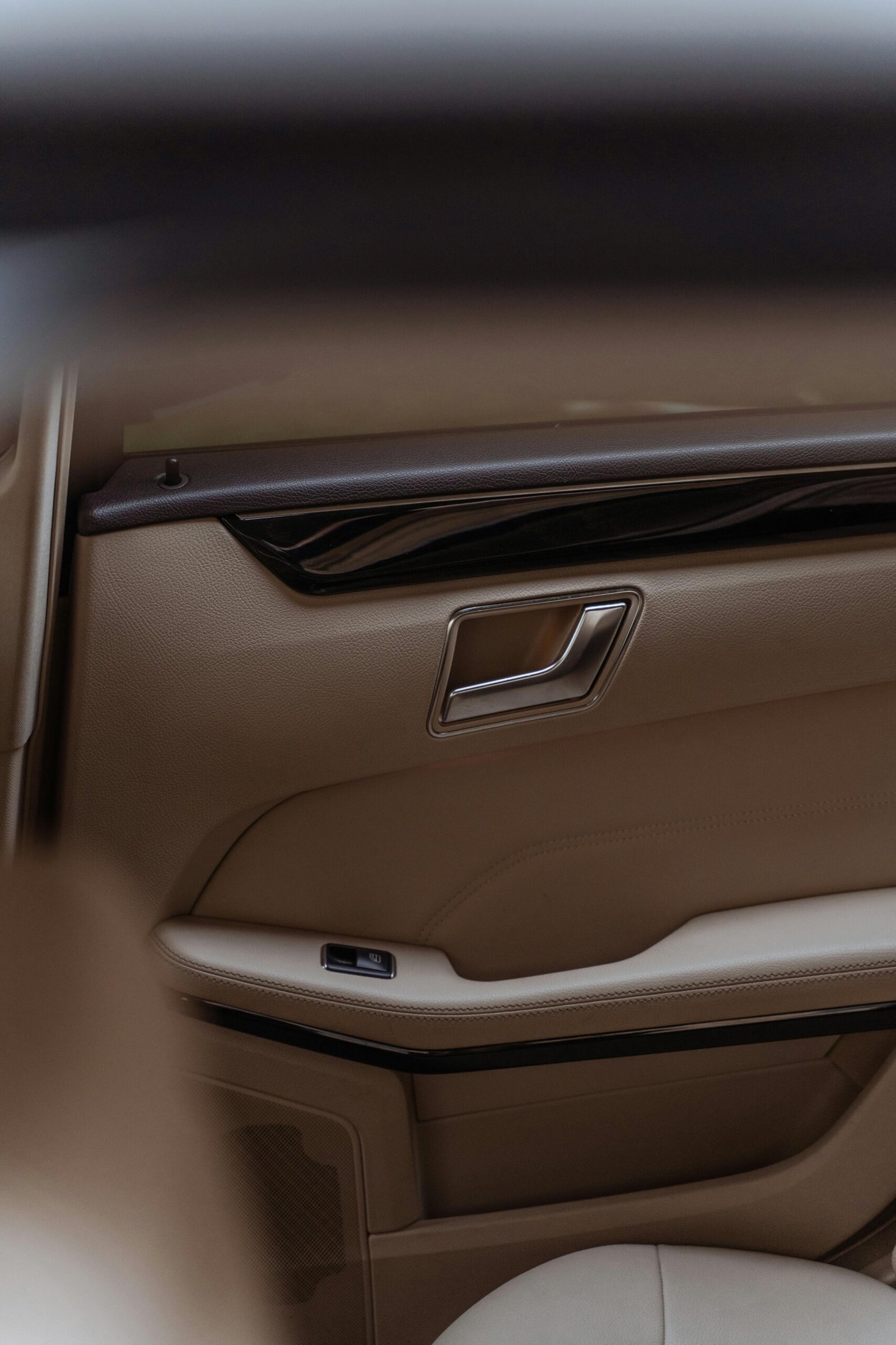 Close-up of a modern tan leather car door interior with elegant design.